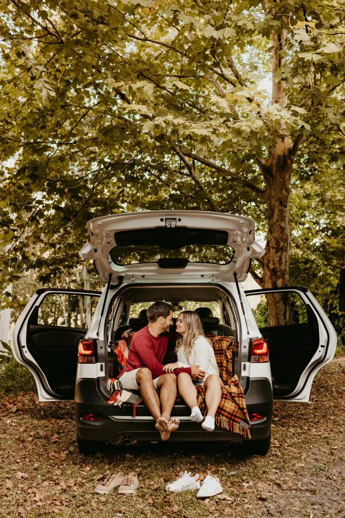 Couple sitting on hatchback of a car