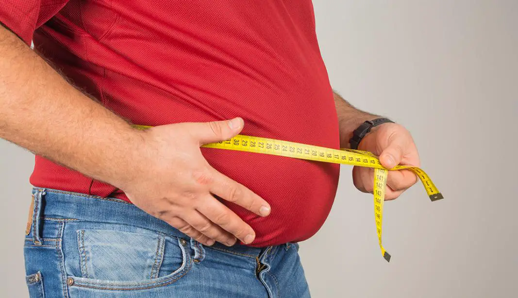 A man measuring his belly with a measuring tape