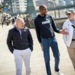 a man talking happily with his 2 other friends walking with them on a roadside