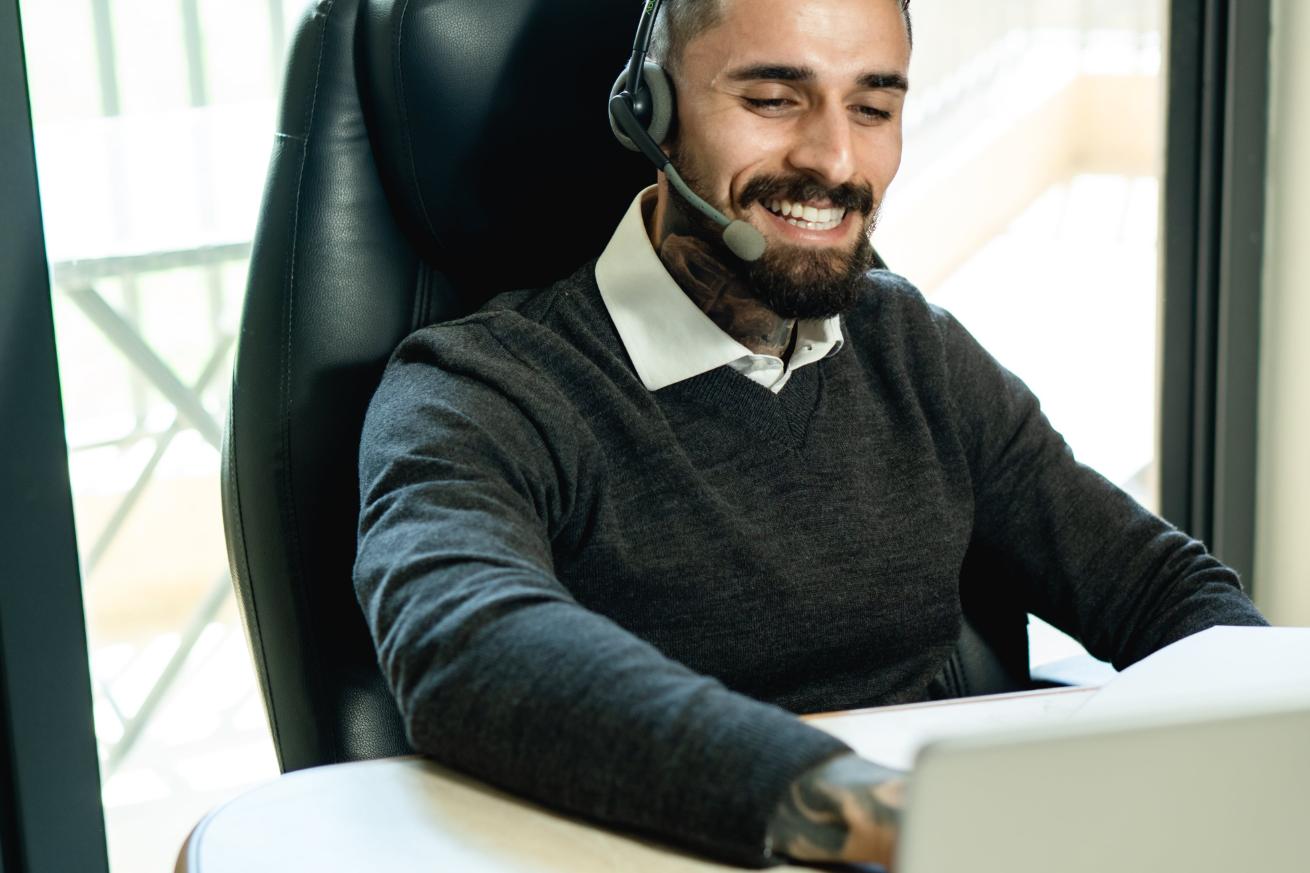 a person working on his laptop while talking to someone in a good mood