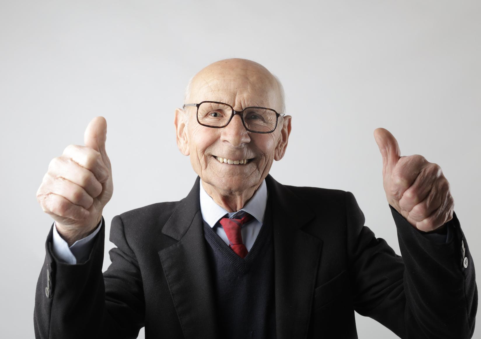 An old man doing thumbs up- looking positive in a good mood