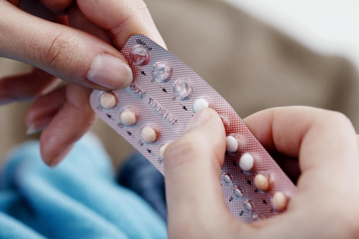 The female hands holding birth control pills
