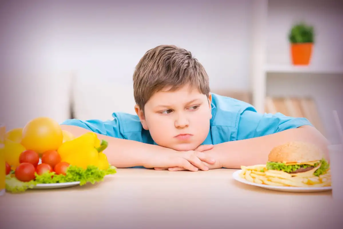 A boy watching food in front of him on a table