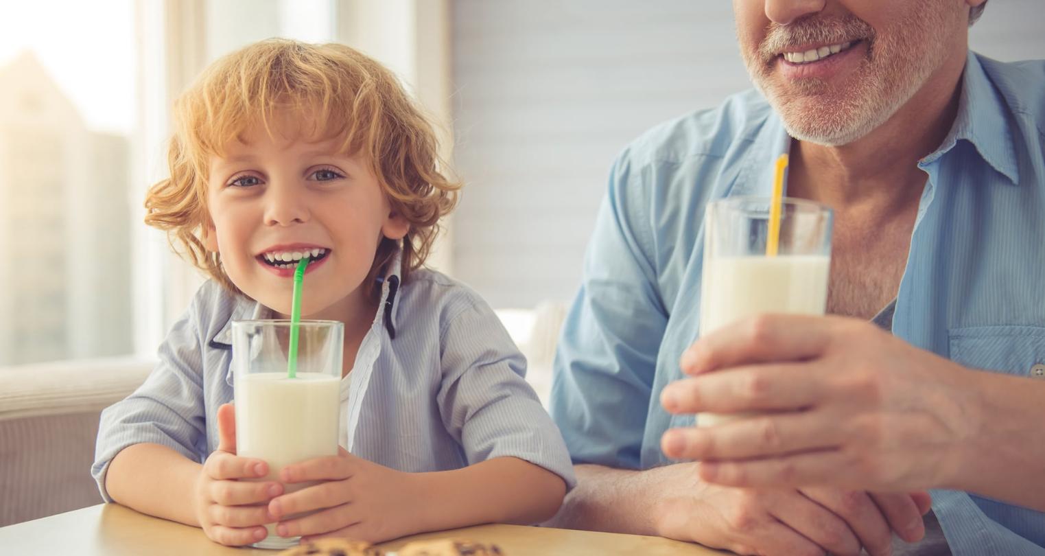 A boy and an old man sipping milk and laughing
