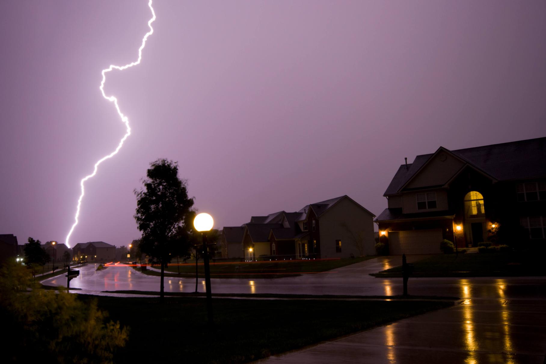 A thunderbolt striking houses across a peaceful road