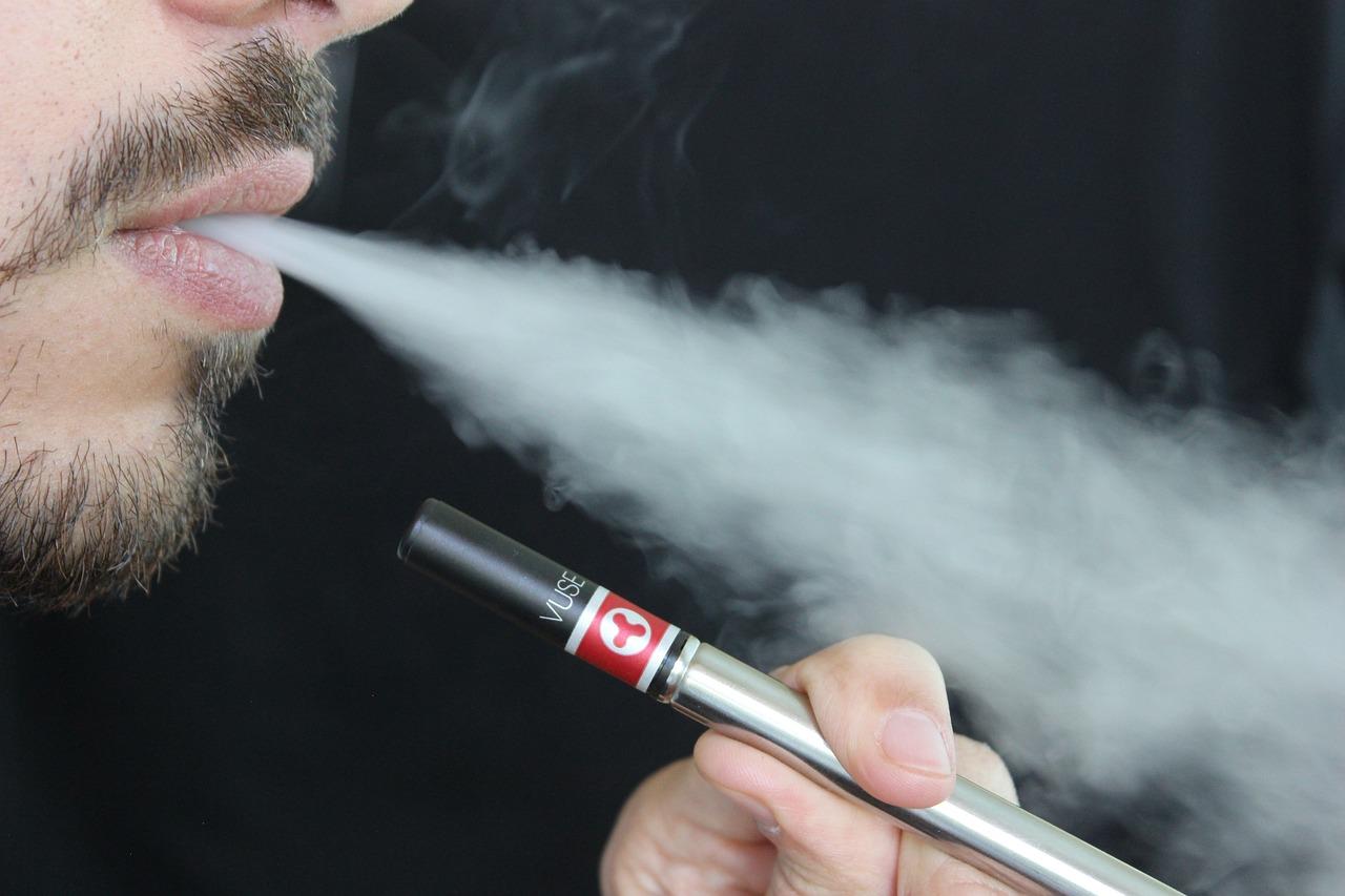 A person with a black background shown to be vaping