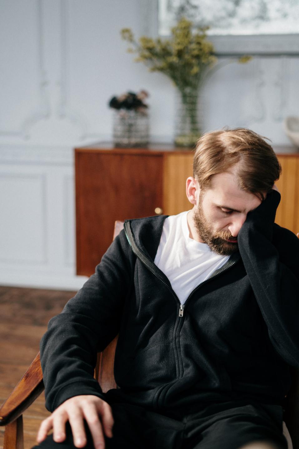a sad person sitting on the chair in his home 