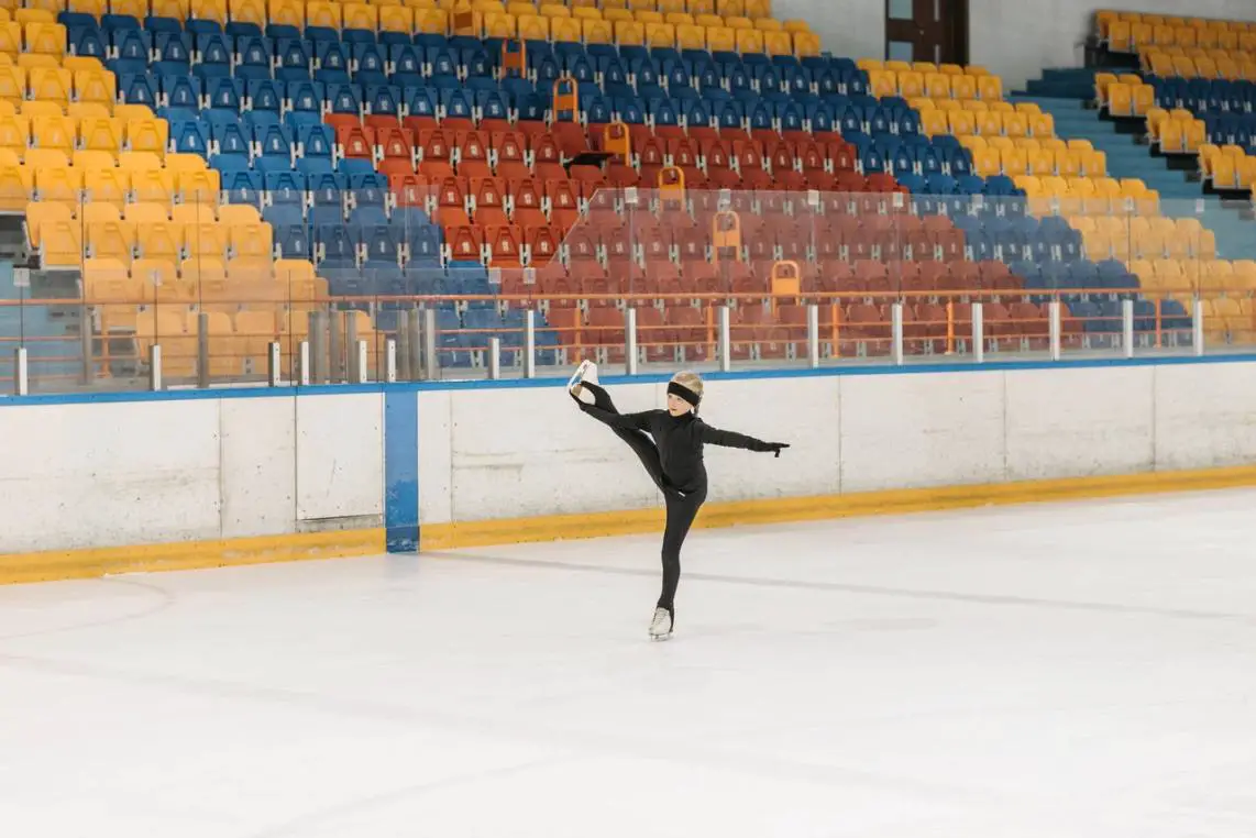  A girl gliding on ice, skillfully balancing on one leg with the other lifted in the air. 