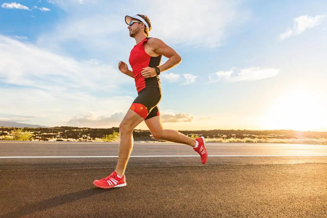 A man wearing vibrant red running gear running under the heat of the sun