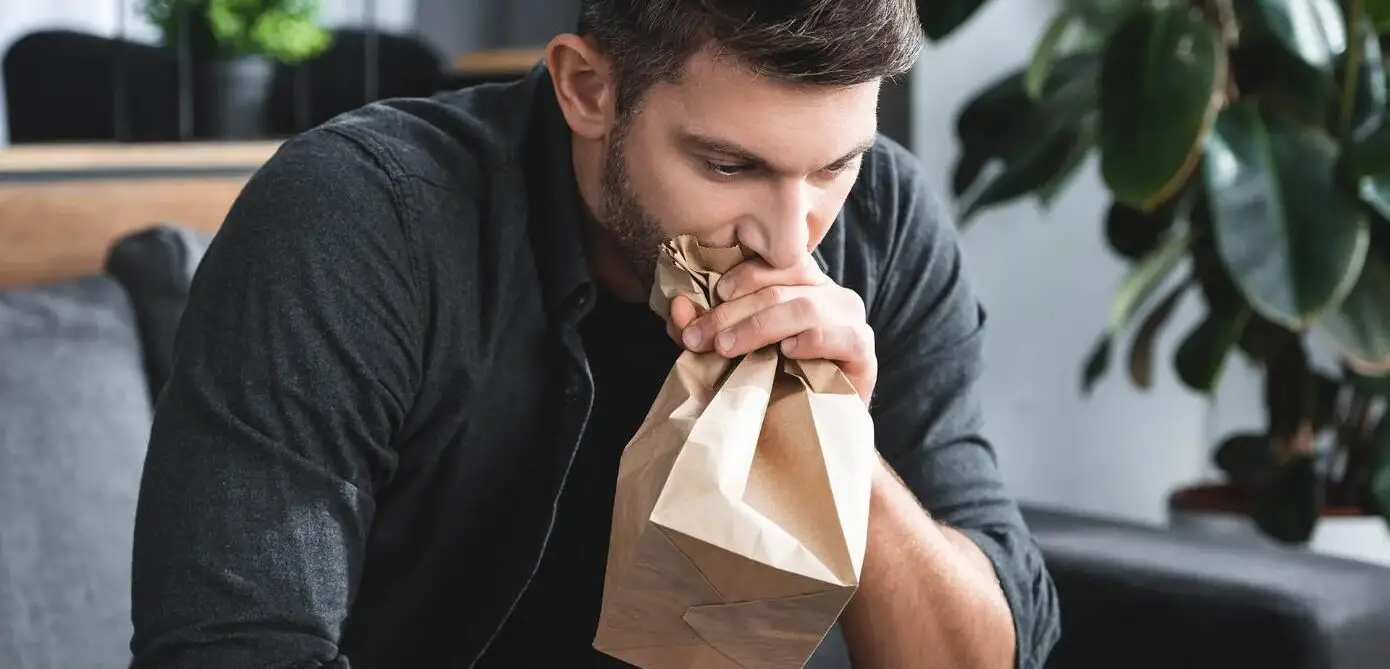 A man breathing in a paper bag