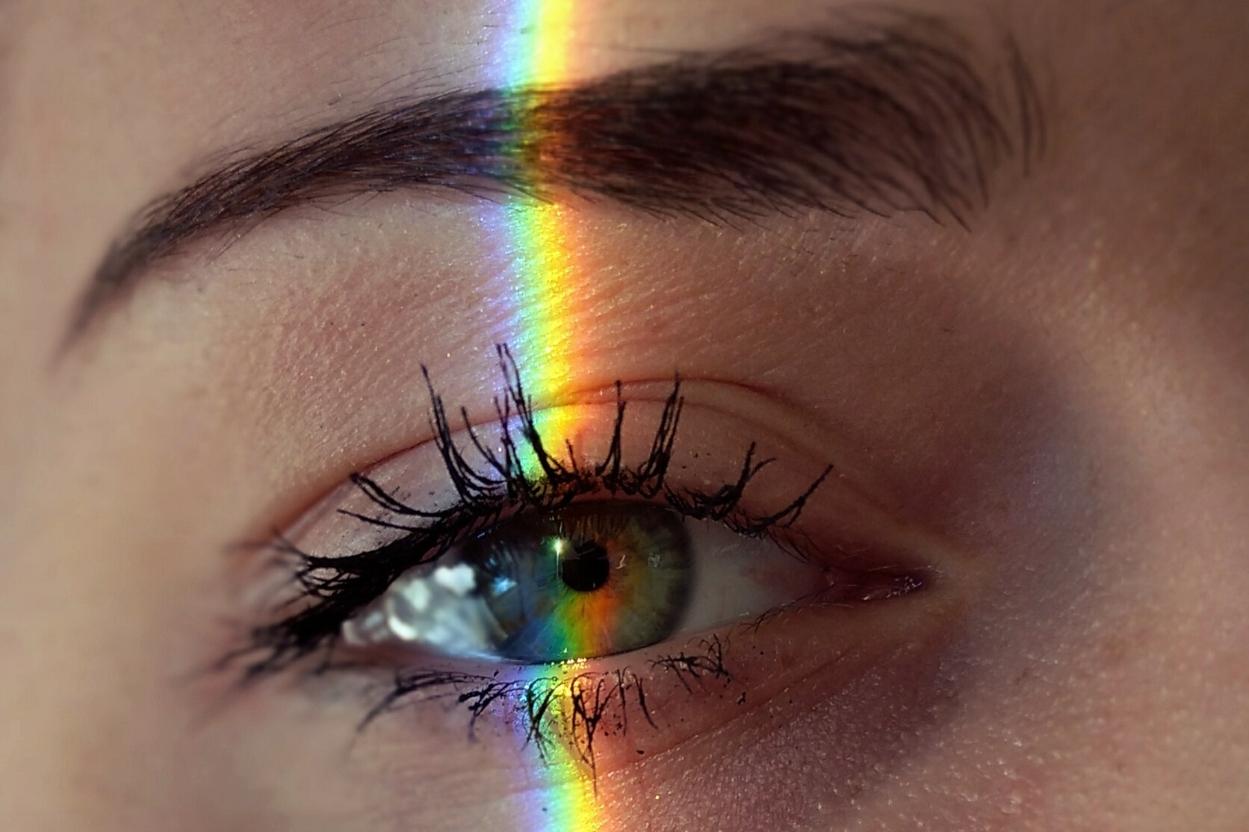 Close-up of a female eye illuminated by colored light.