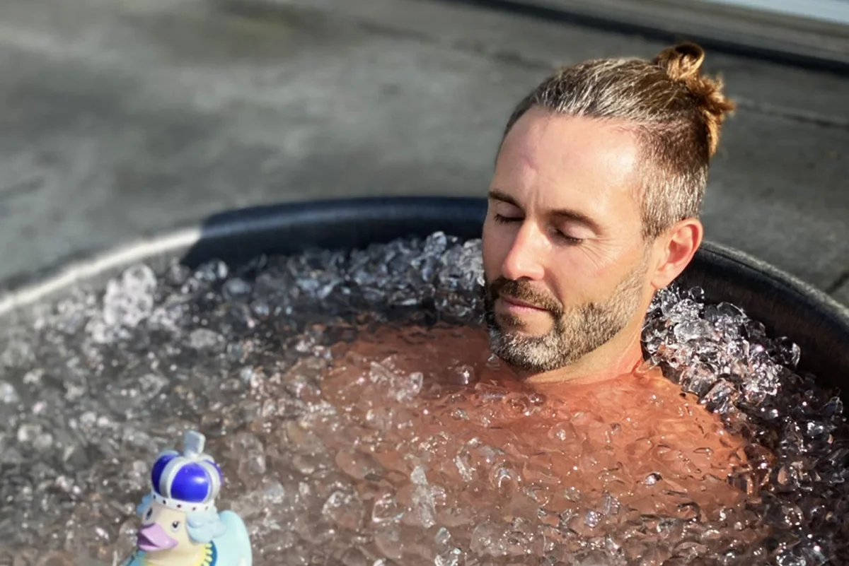 A man experiencing contrast therapy by submerging in a water tub