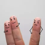 Three finger puppets: two close together, expressing love, while the third one, standing apart, showing jealousy and anger