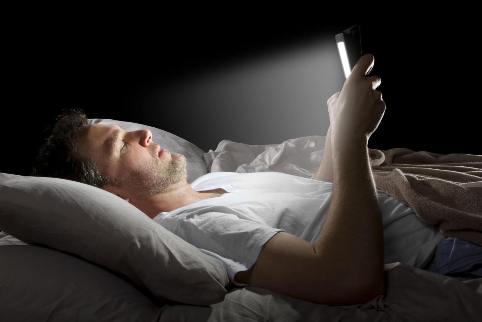 A man using his phone at night while lying in bed