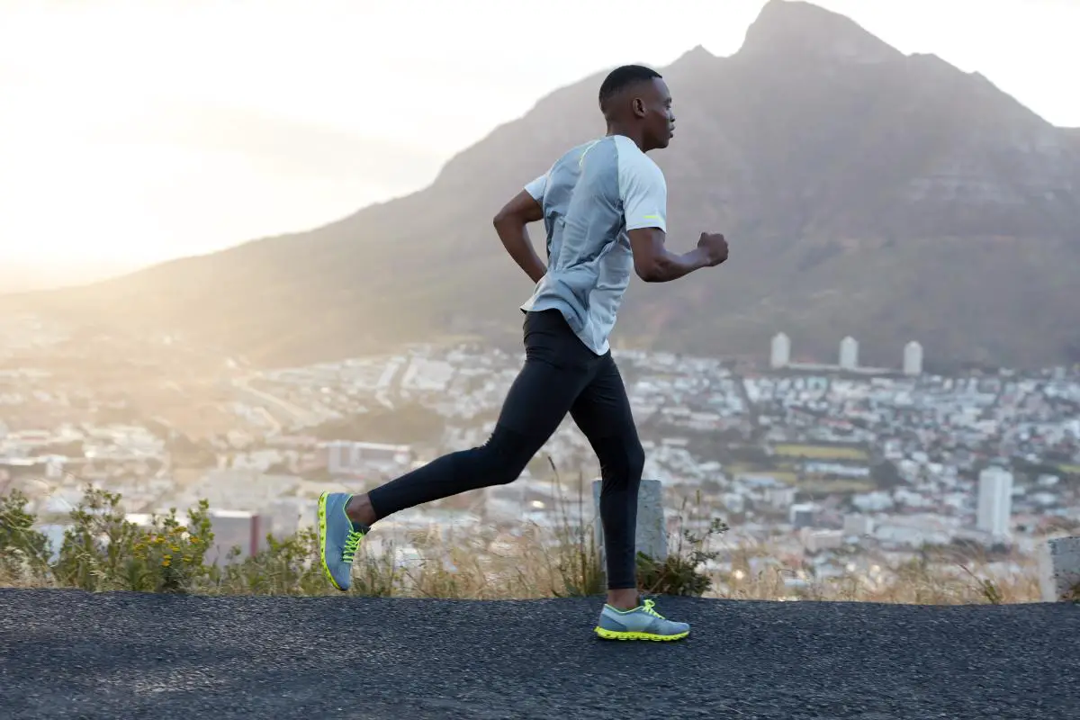 A Man wearing Trousers and Joggers Running in a mountainous area with full energy