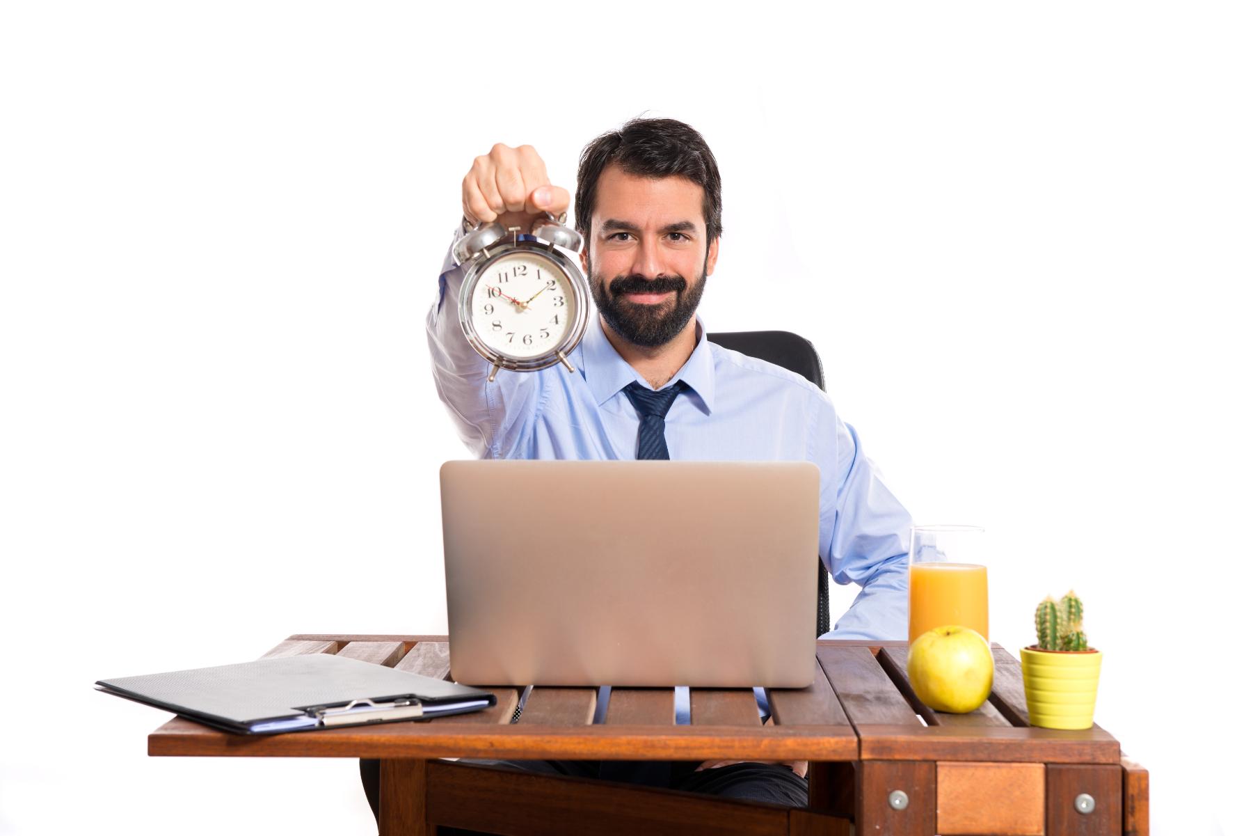 A person sitting in front of his laptop for his official work- showing the clock in his hand with a smile after finising the work on time