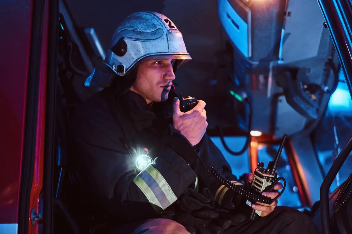 A firefighter wearing his uniform, talking to his fellow on the phone, instructing him and leading his