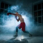 A young athlete practicing shadow boxing and punching in a room with bluish smoke