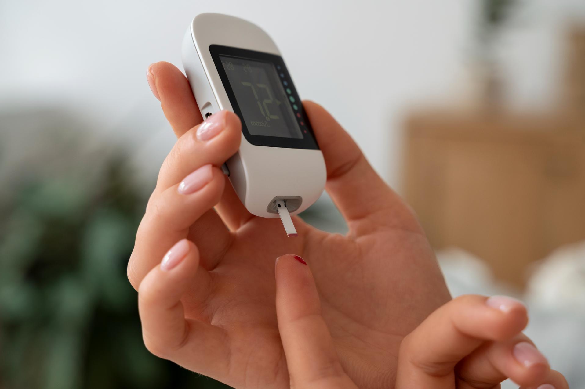 a person holding a glucose checking apparatus in one hand while checking his glucose level