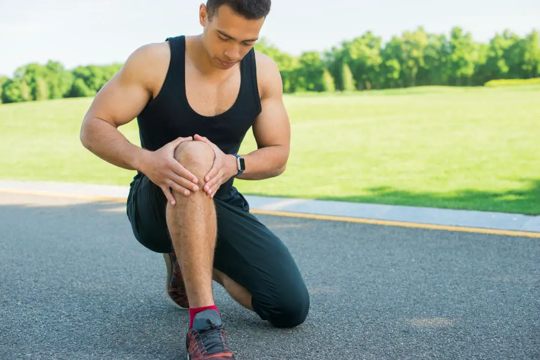 A sportsman during his running holding his knee due to pain