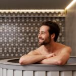 A person sitting relaxed and stress free in a sauna room smiling