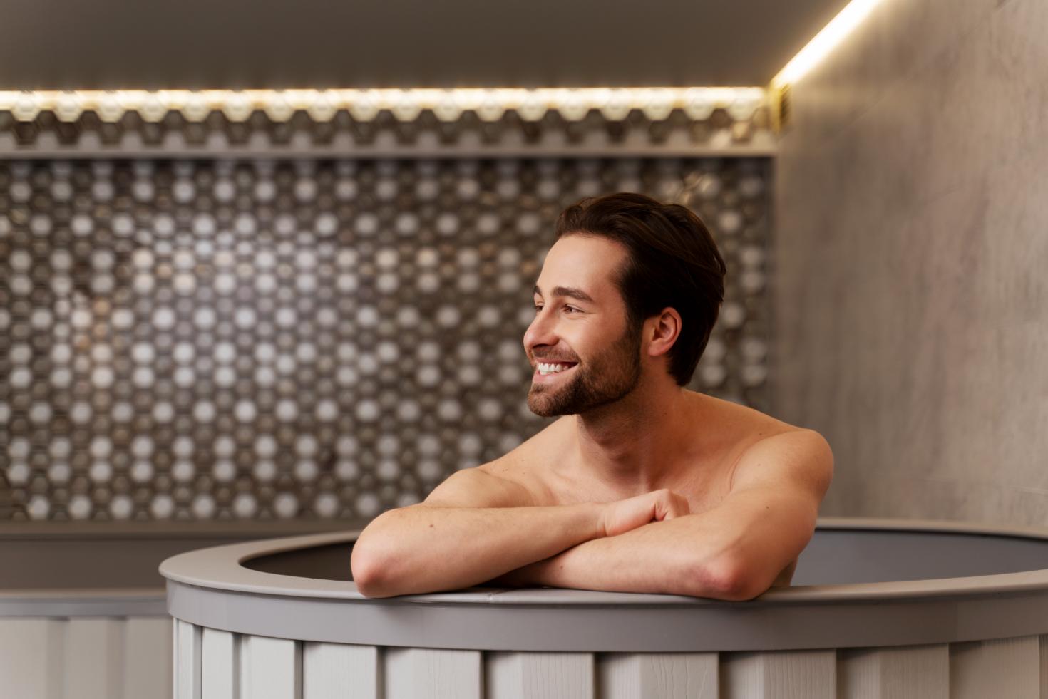 A person sitting relaxed and stress free in a sauna room smiling