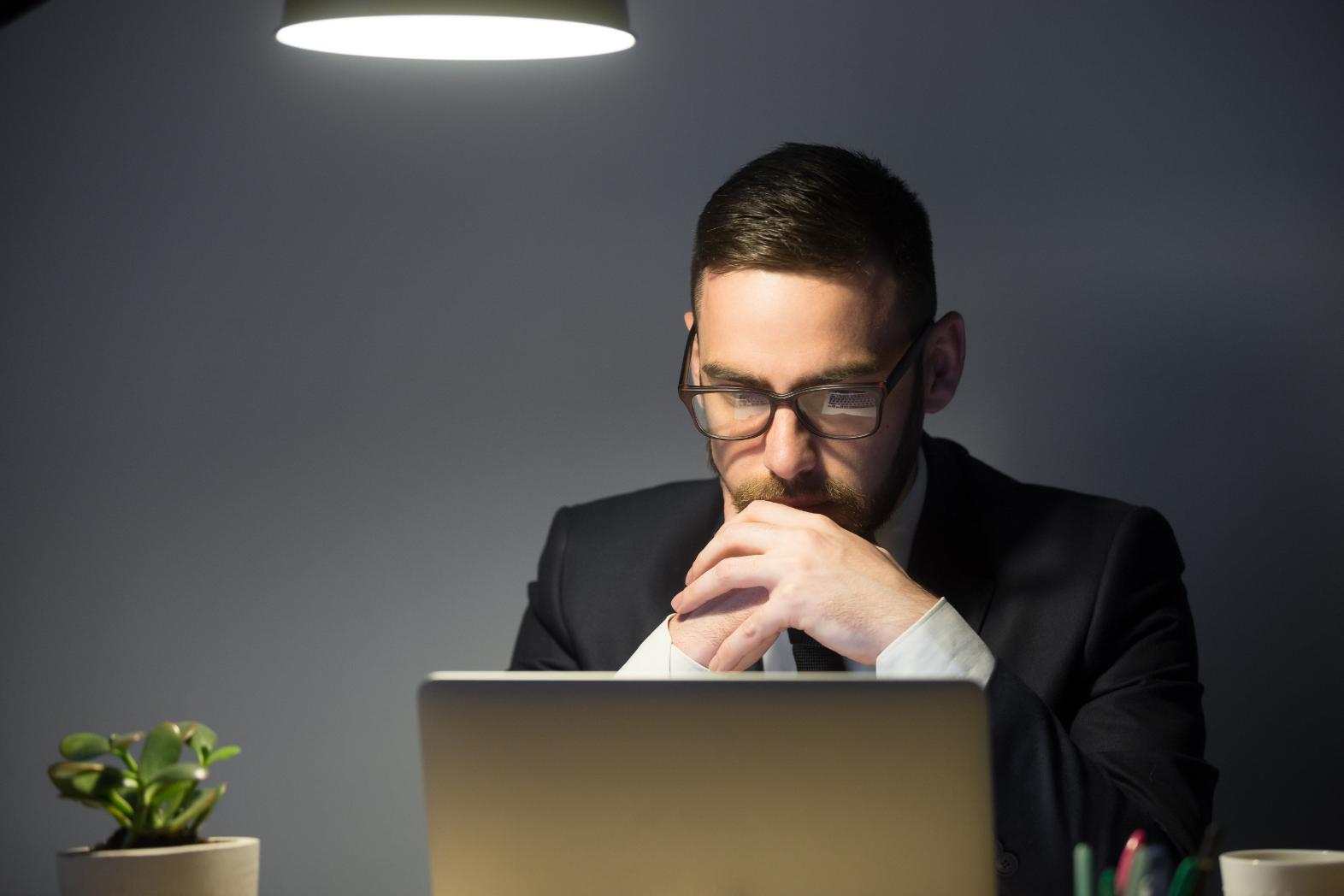 A person looking at his laptop in his front thinking deeply and trying to focus on the problem