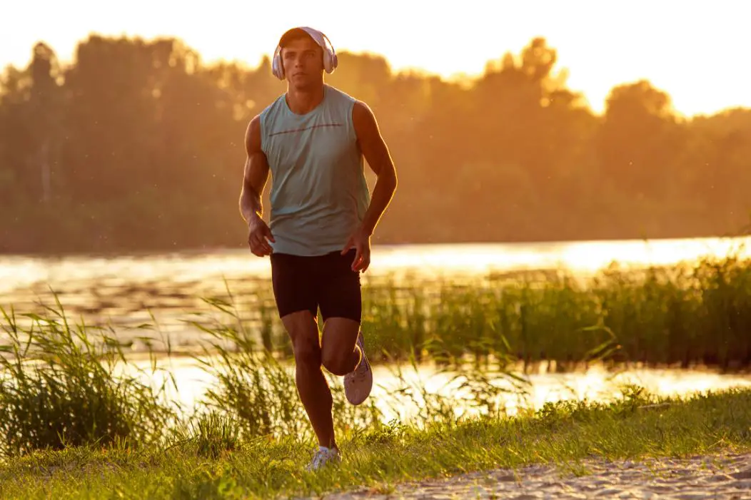 A young athletic person while listening to the music jogging early in the morning, the body getting sunlight helping in the production of vitamin d