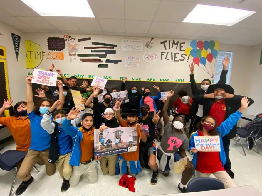 Children celebrating after-school program, joyfully raising colorful placards.