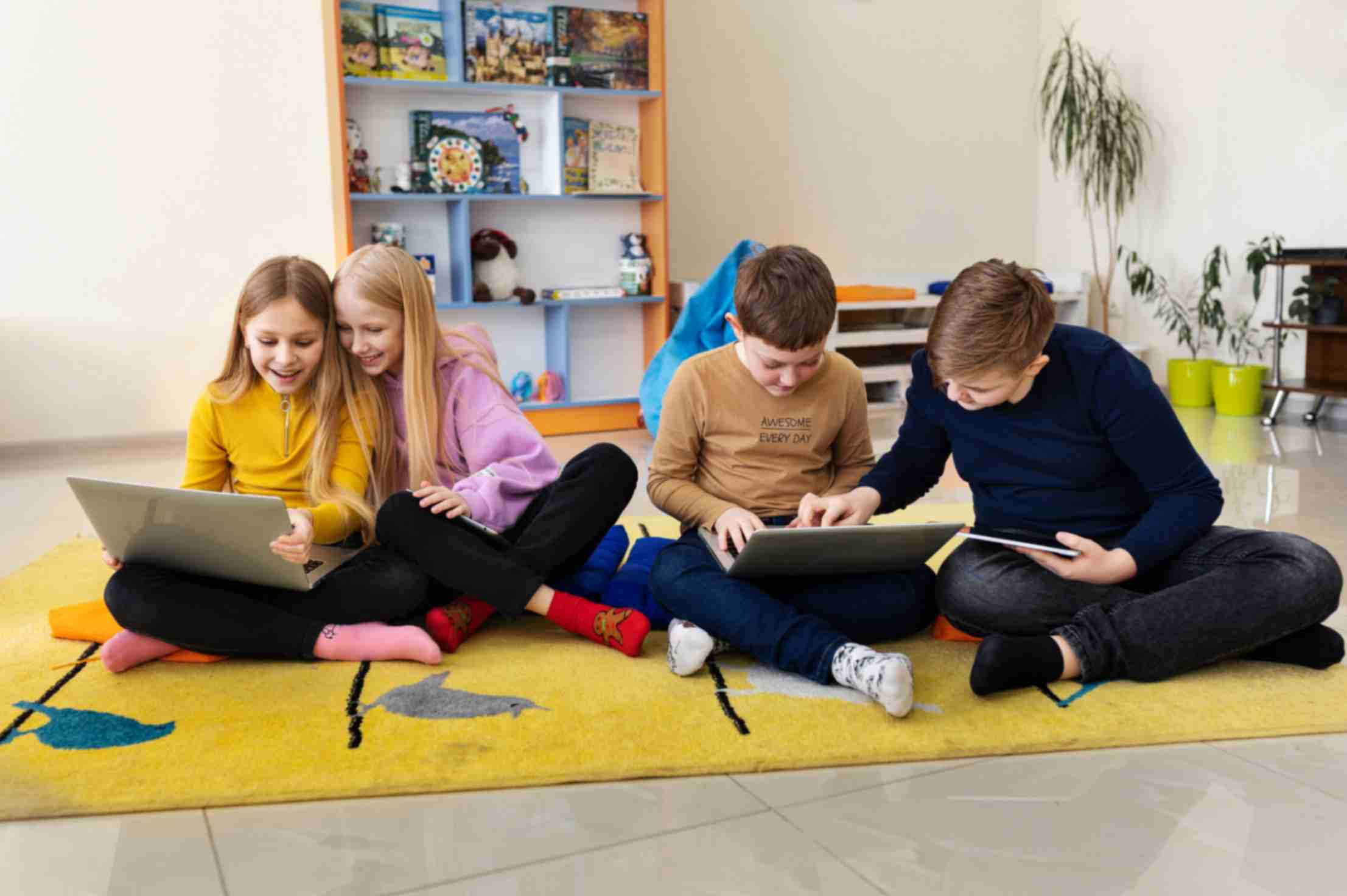 Four kids working together using their laptops and tablets in afterschool programs.