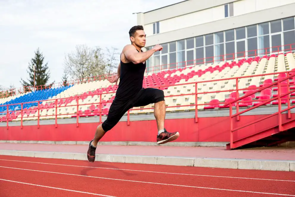 A young Athlete running in a track alone with both his feet off the ground