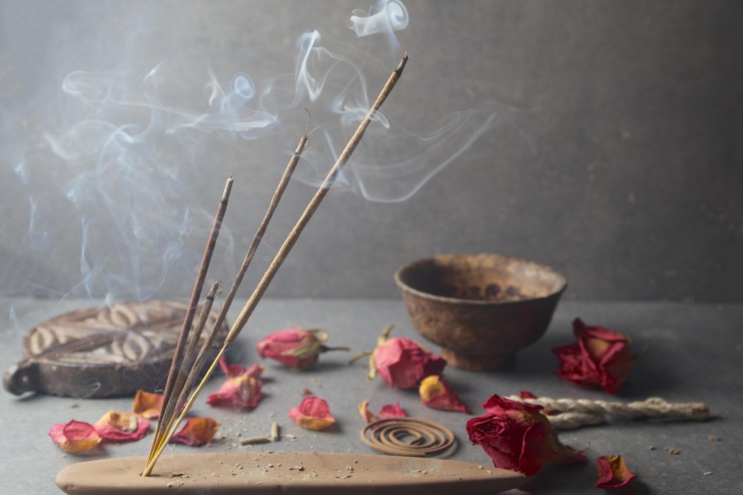 Burning incense sticks along with coils, partially dried petals, and rose flowers.