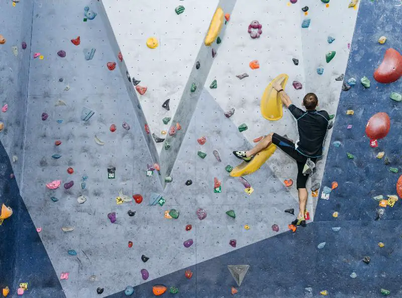 A man bouldering, navigating a rock wall without ropes for a challenging and dynamic climbing experience.