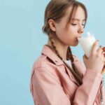 Young attractive girl with two braids drinking milk