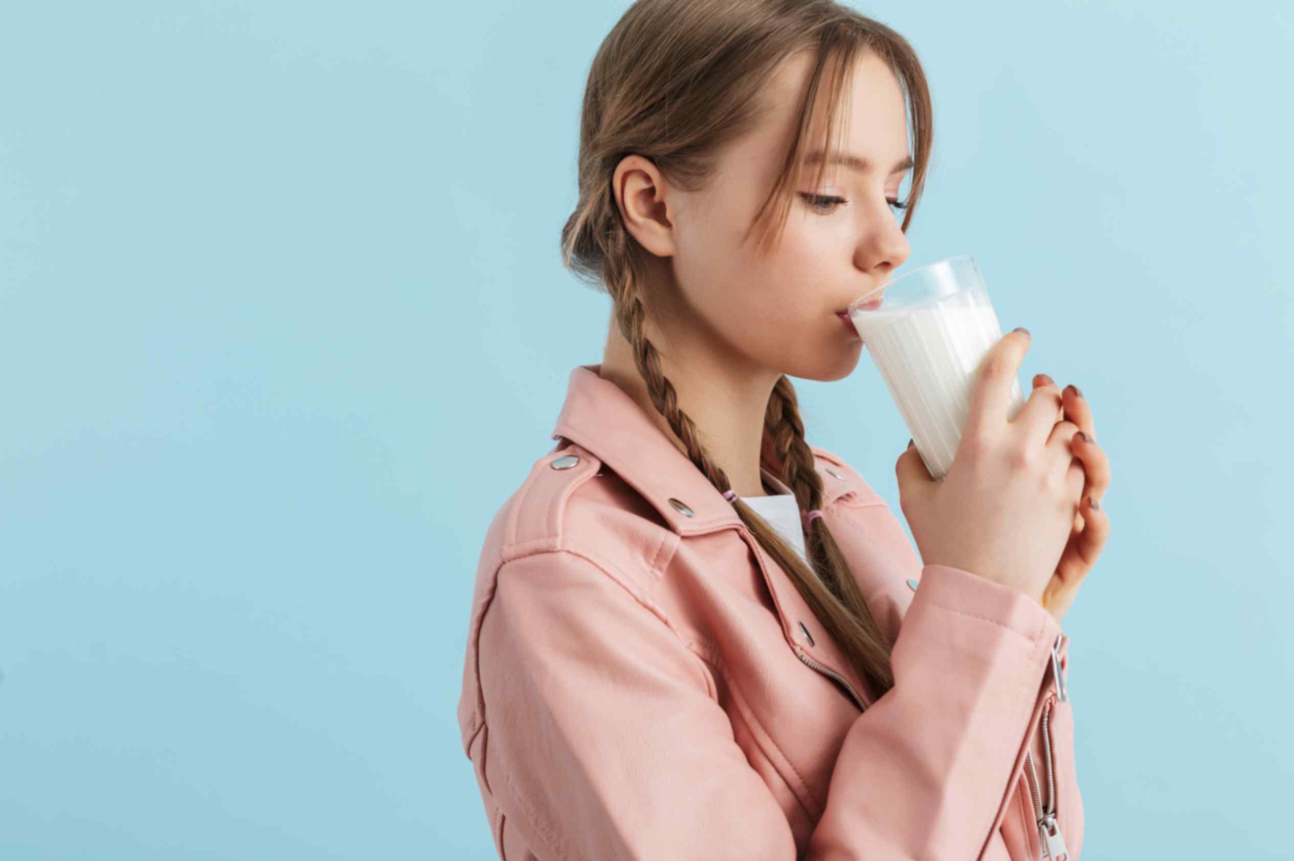 Young attractive girl with two braids drinking milk