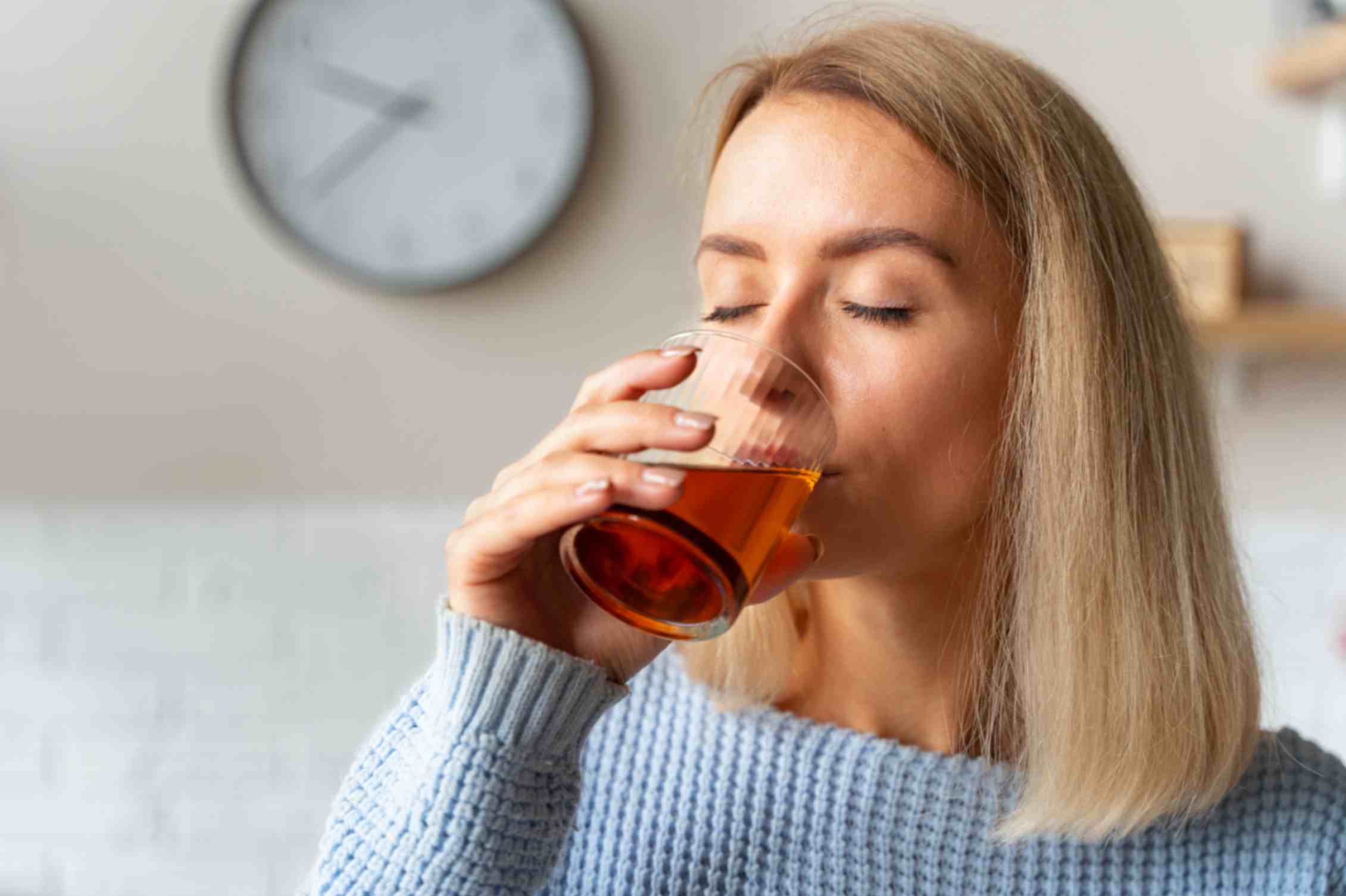 A young girl drinking a glass of ginger tea
