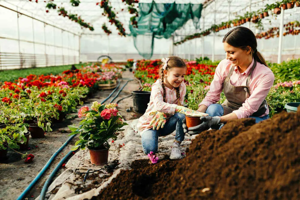 Happy Mother Educating her Daughter in a Raised Garden Bed