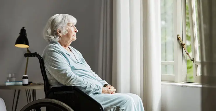 A lonely elderly woman sitting in her wheelchair by the window