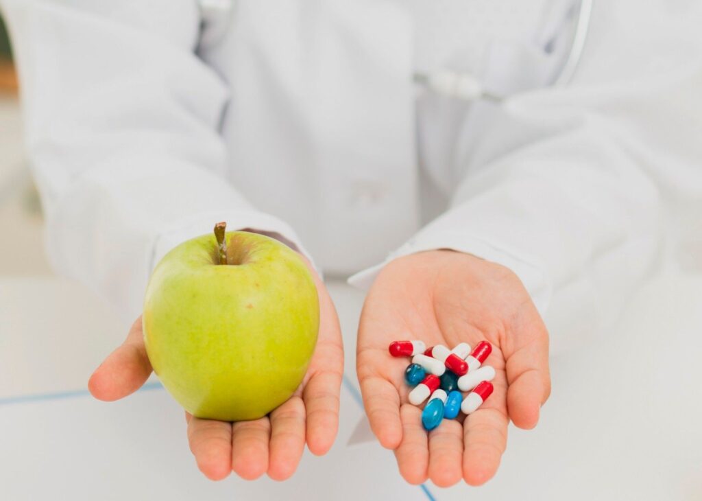Doctor is helding apple in one hand and medicines in the other hand 
