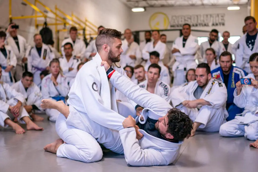 Dynamic scene of a Mixed Martial Arts class with two men engaged in intense practice, while others are sitting and watching