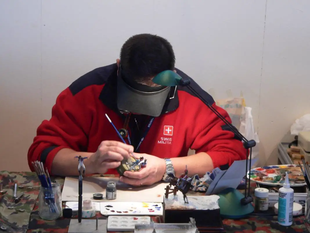 A man is busy in coloring a miniature model.
