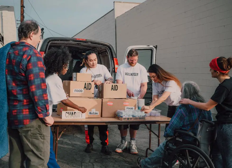 Some volunteers wearing white shirts distributing free food and medicine to the needy people