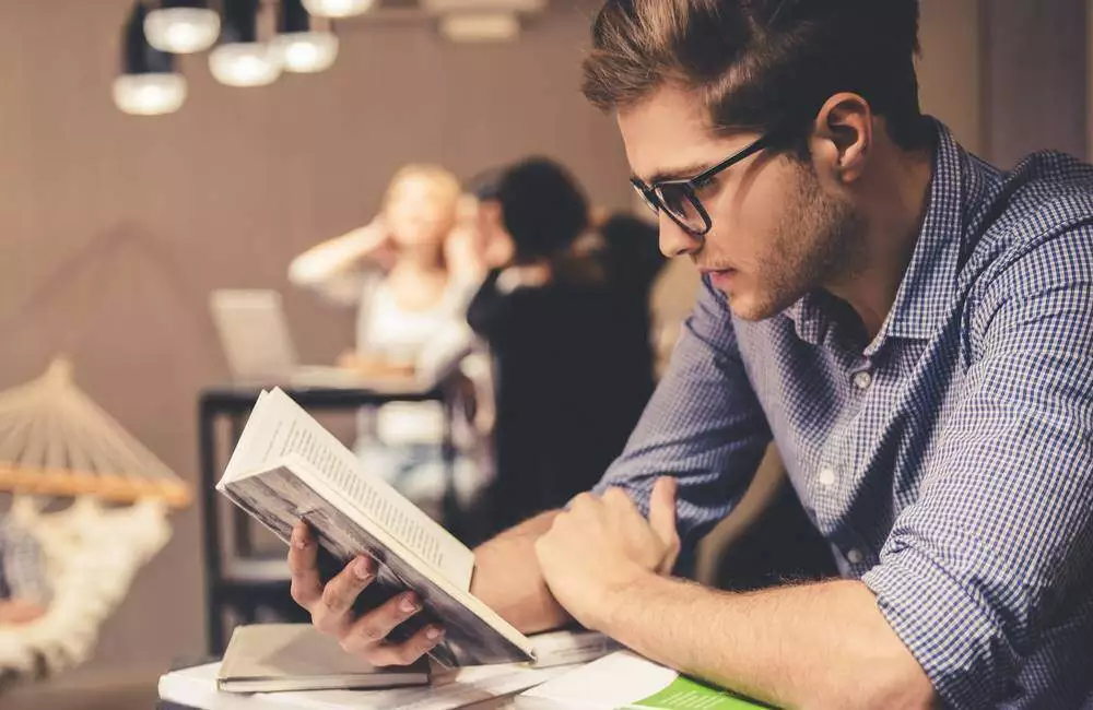 A young man keenly absorbed in a book.