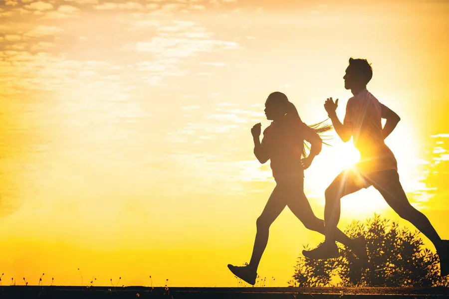 Silhouettes of a couple running against a vibrant yellow horizon