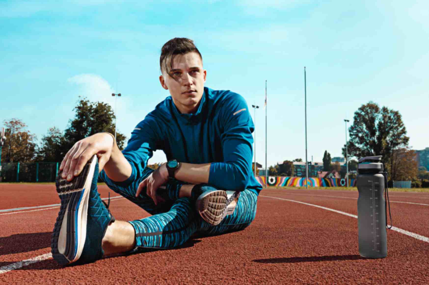 Man runner stretching legs preparing run training stadium tracks doing warm up