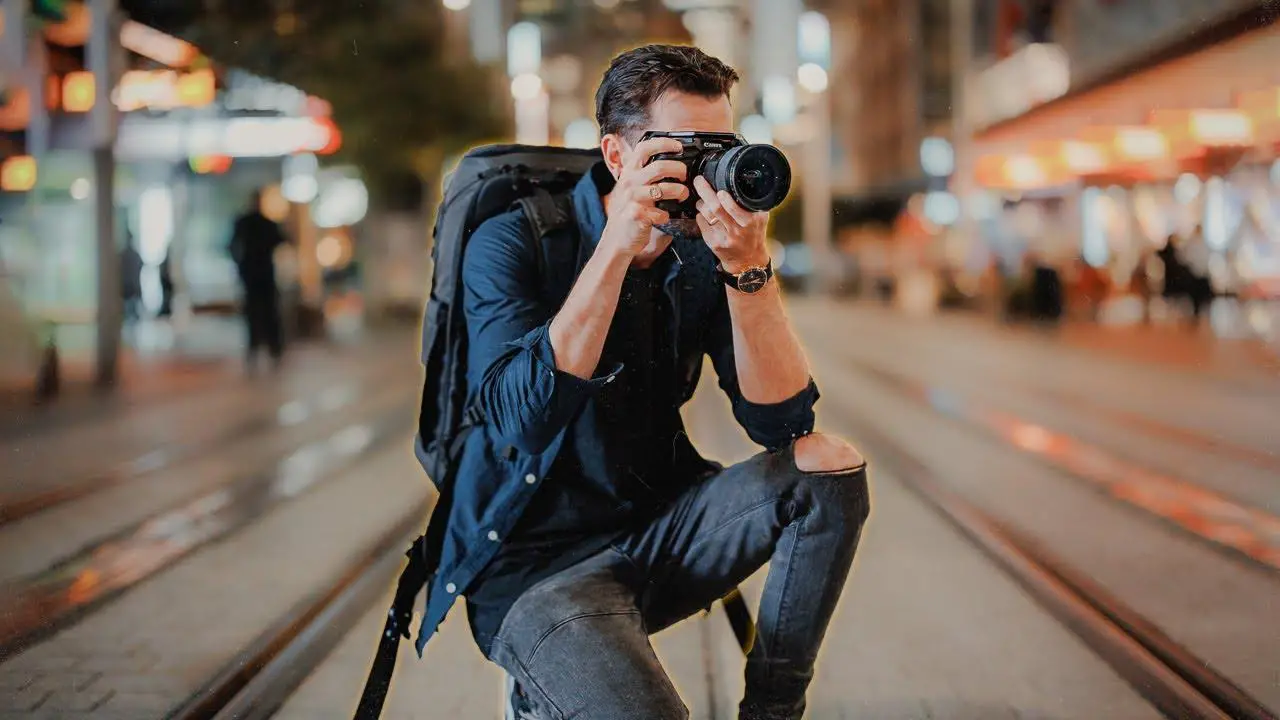 A man, on his knee, capturing candid shots on a street.