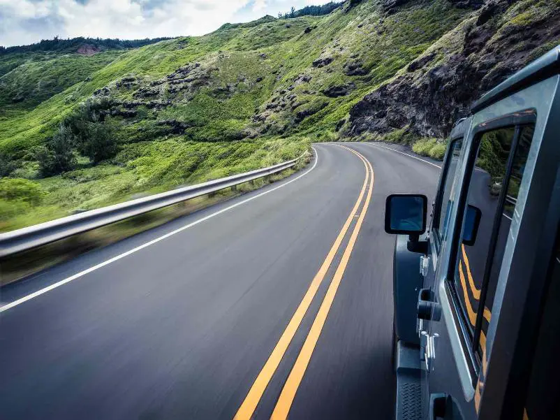 A car drives along a curvy road in beautiful green mountains
