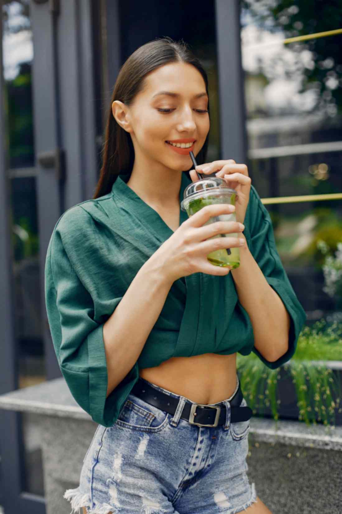 Young Woman Drinking Green Juice Outside the CAFE