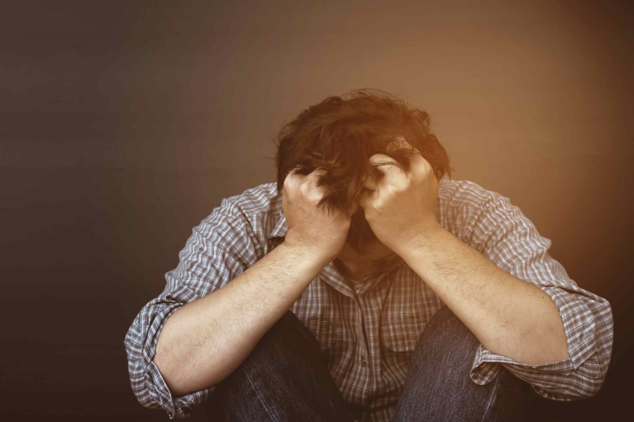 A man suffering from mental illness holding his head 