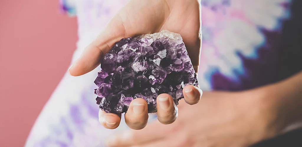 A female hand holding amethyst stone